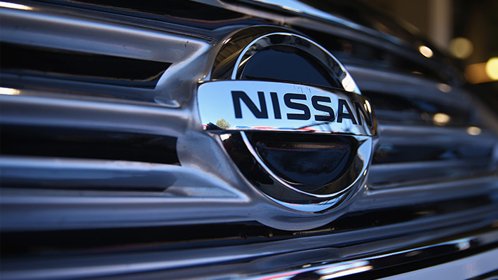 The Nissan logo on the front grille of a vehicle.