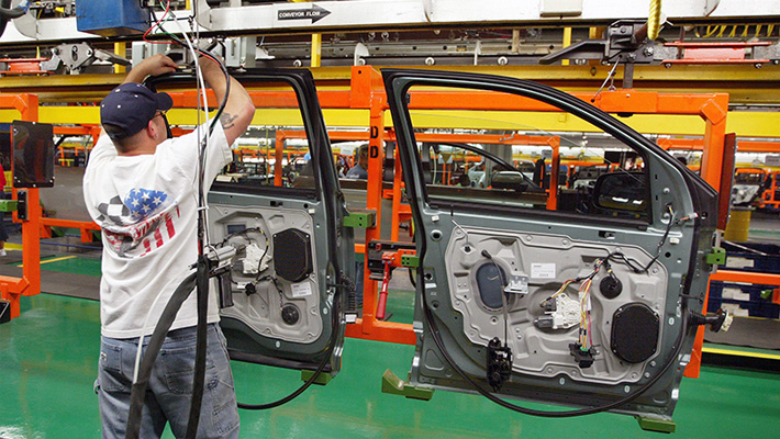 A line worker handles a door at a Ford plant.