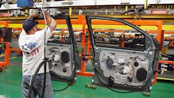 A line worker handles a door at a Ford plant. A line worker handles a door at a Ford plant.