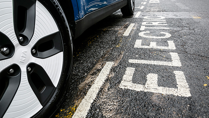 An electric Kia parked on the street.