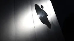 An Apple logo cast in light on a shadowed wall.