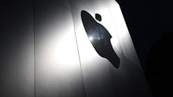 An Apple logo cast in light on a shadowed wall. An Apple logo cast in light on a shadowed wall.