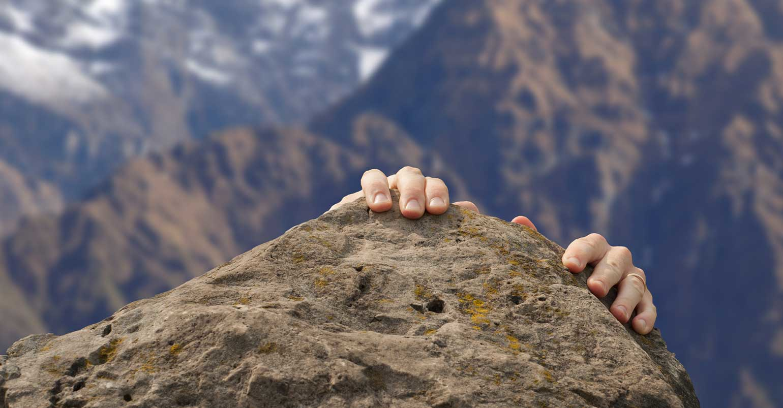 man struggles to reach mountain top