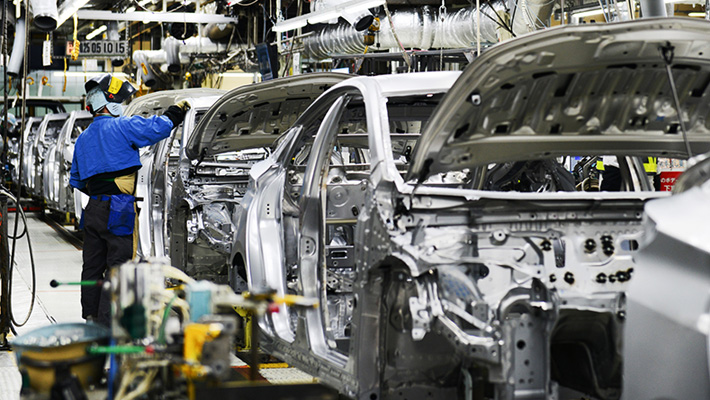 A plant employee works on a car on the assembly line.