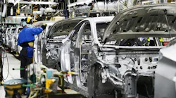 A plant employee works on a car on the assembly line.