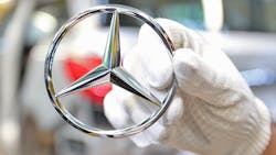 A gloved hand holds a Mercedes-Benz logo hood ornament. A gloved hand holds a Mercedes-Benz logo hood ornament.