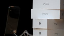 A pile of Apple iPhone X boxes next to a new phone on display. A pile of Apple iPhone X boxes next to a new phone on display.