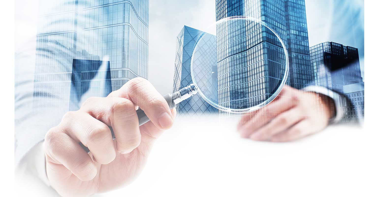 Businessman holding magnifying glass to buildings