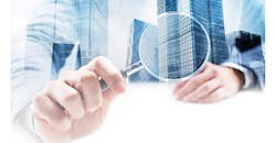 Businessman holding magnifying glass to buildings Businessman holding magnifying glass to buildings