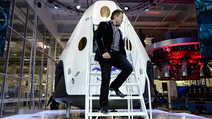 Elon Musk descends from a Dragon V2 spacecraft.