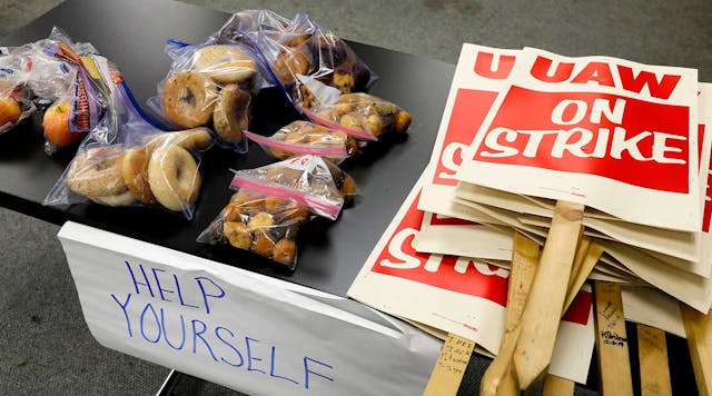 Food donations sit on a table next to a stack of UAW strike signs in Lake Orion, Michigan