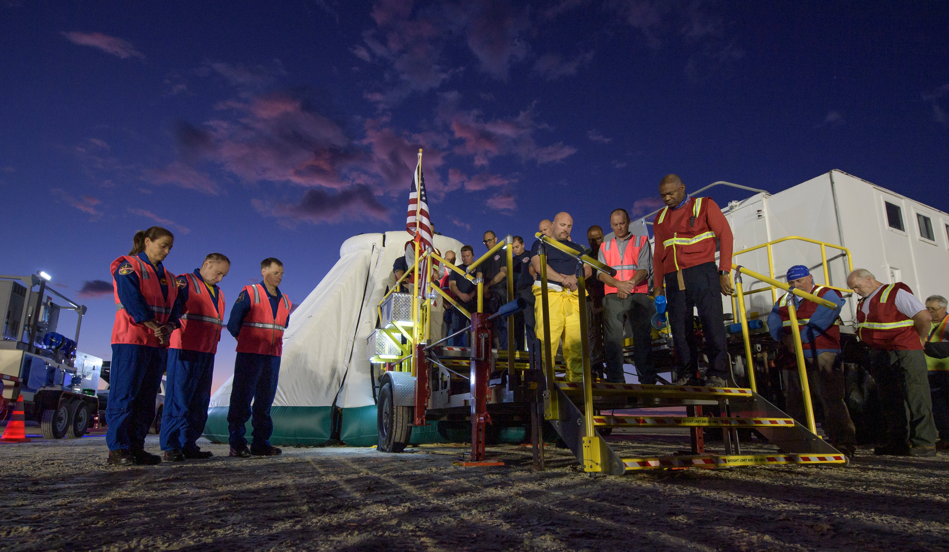 NASA astronauts Nicole Mann and Mike Fincke and Boeing astronaut Chris Ferguson observe a moment of silence with teams from NASA, Boeing and the White Sands Missile Range, honoring the victims of the Sept. 11 terrorist attacks, September 11, 2019 at the White Sands Missile Range outside Las Cruces, New Mexico. The joint teams gathered in the desert to rehearse landing and crew extrication from Boeings CST-100 Starliner, which will be used to carry humans to the International Space Station. Mann, Fincke and Ferguson will fly to the space station aboard the Starliner for the Boeing Crew Flight Test mission.