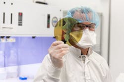 A scientist at SK Siltron CSS holds a silicon carbide wafer produced at the company's Michigan facility. A scientist at SK Siltron CSS holds a silicon carbide wafer produced at the company's Michigan facility.