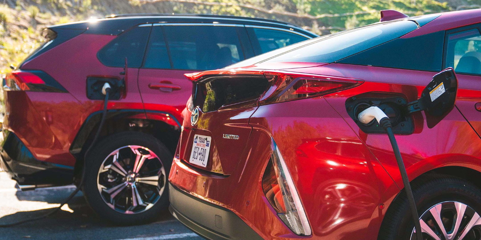 A photo of two red Toyota plug-in hybrid vehicles.