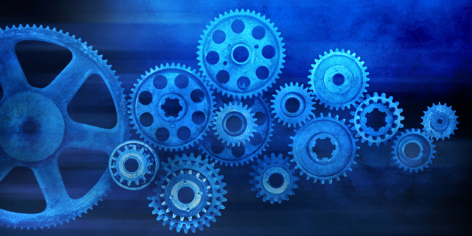A system of gears against a blue background. An abstract representation of manufacturing and industry.