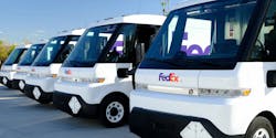 A lineup of BrightDrop EV600 electric delivery vans in FedEx livery. A lineup of BrightDrop EV600 electric delivery vans in FedEx livery.