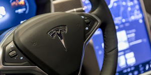 A closeup of the Tesla logo on the steering wheel of a Tesla vehicle.