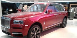 A red Rolls-Royce Cullinan SUV at an auto show.