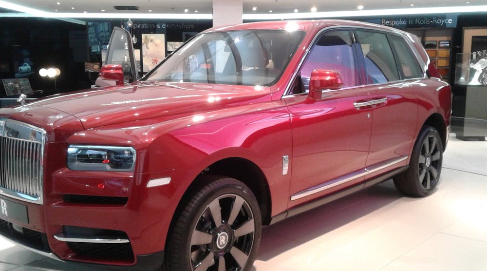 A red Rolls-Royce Cullinan SUV at an auto show.