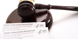 A gavel resting near CDC-issued COVID-19 vaccination record cards.