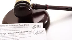 A gavel resting near CDC-issued COVID-19 vaccination record cards.