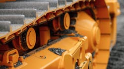 A closeup on the treads of heavy construction equipment painted bright yellow.