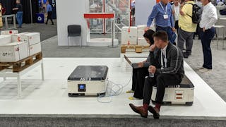Employees use an ABB autonomous mobile robot (AMR) as a seat at the company&apos;s Automate booth.