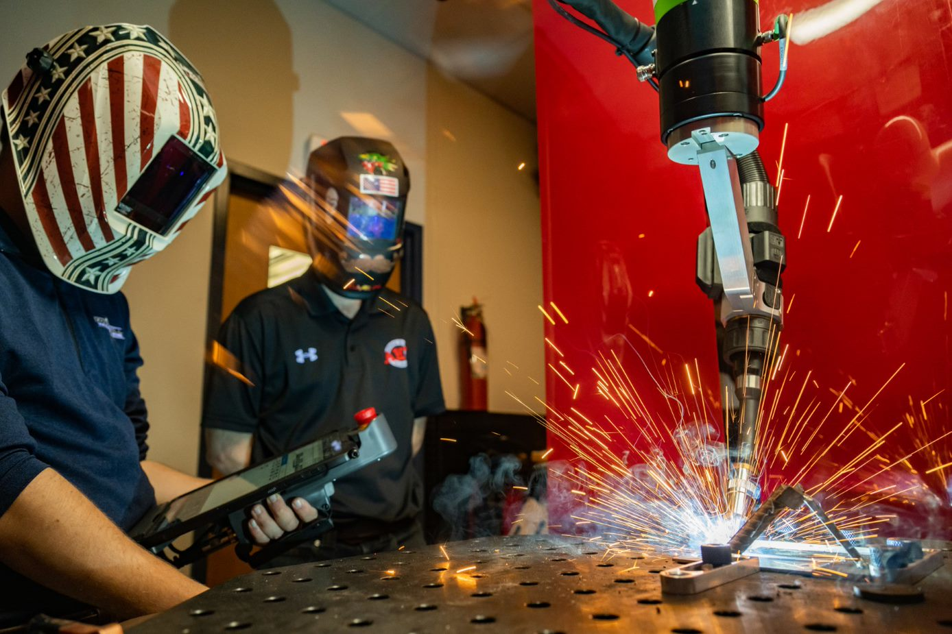 Joel Sander, left, and Brian Stempka, right, working at McDowell Manufacturing&rsquo;s robotic welder.