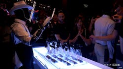 A Telsa Optimus robot hands out gift cards at a recent Hollywood event. Though CEO Elon Musk has called the humanoid robots autonomous, human handlers managed the robots via remote control during the event. A Telsa Optimus robot hands out gift cards at a recent Hollywood event. Though CEO Elon Musk has called the humanoid robots autonomous, human handlers managed the robots via remote control during the event.