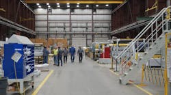 Group of men in center aisle of factory Group of men in center aisle of factory