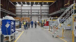 Group of men in center aisle of factory Group of men in center aisle of factory