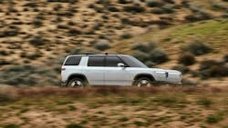 White Rivian R2 driving in dry looking area. White Rivian R2 driving in dry looking area.