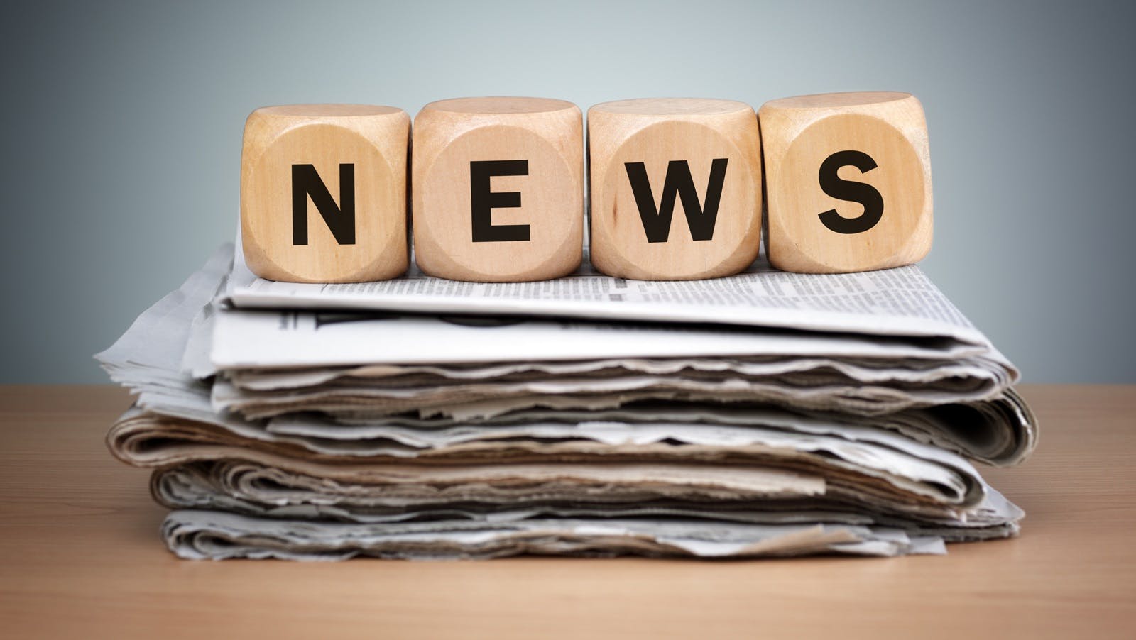 Dice that spell out news on top of a stack of newspapers