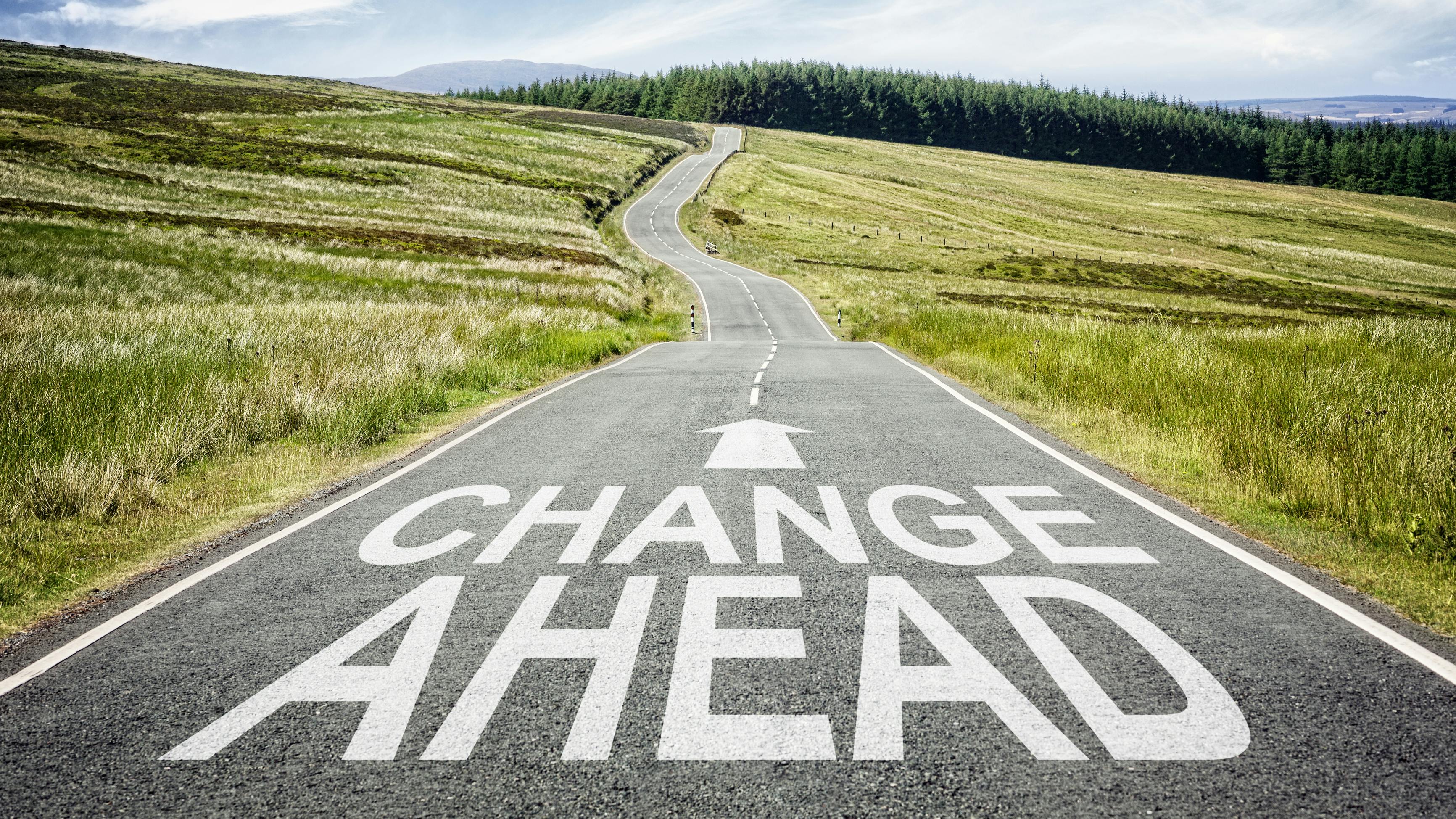 Image of a long road with an arrow and the words 'Change Ahead.'