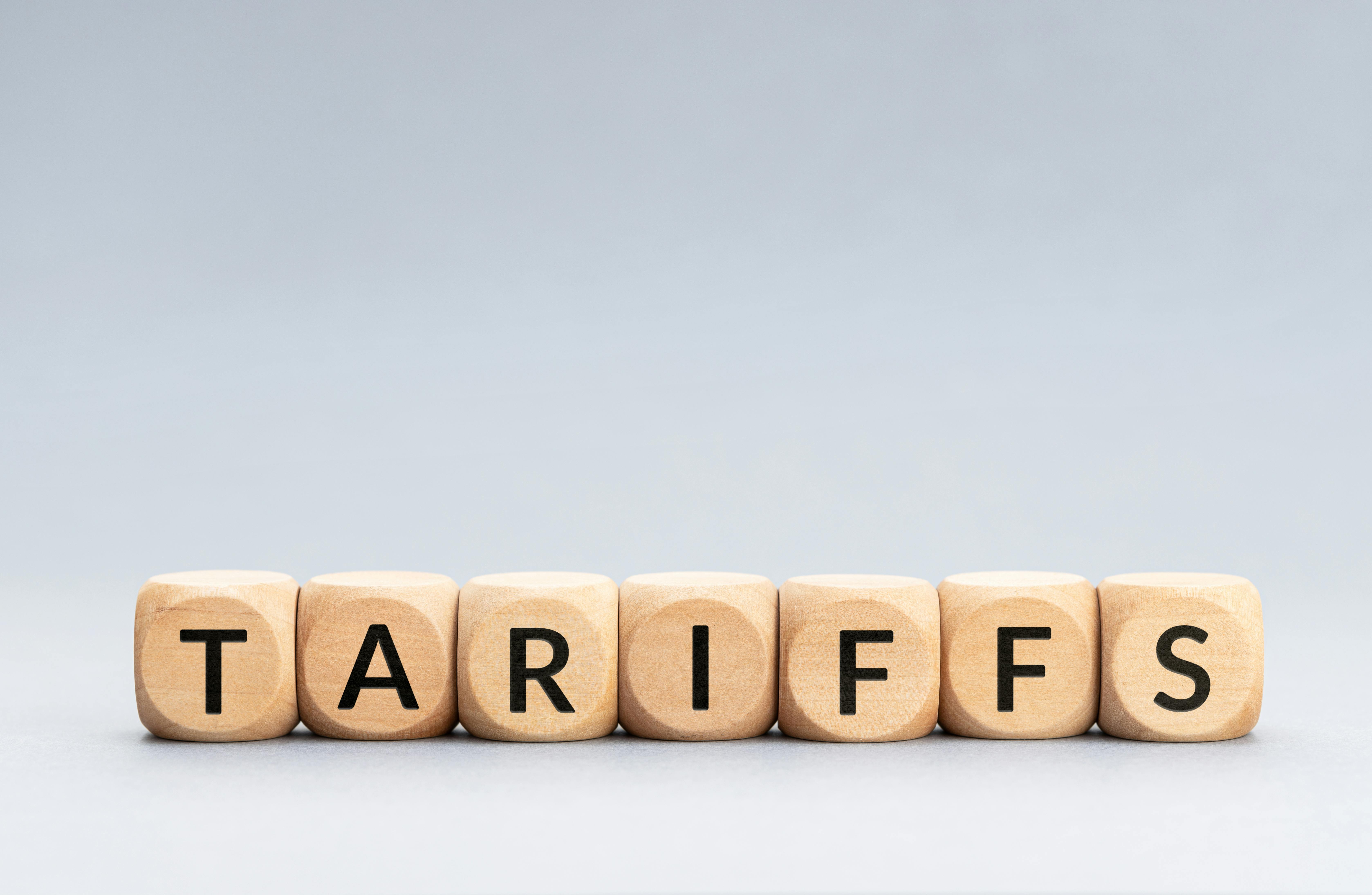 TARIFFS word on wooden blocks isolated on gray background.