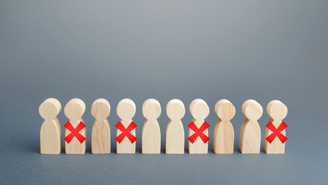 A line of wooden people. Some are crossed out with a red cross.