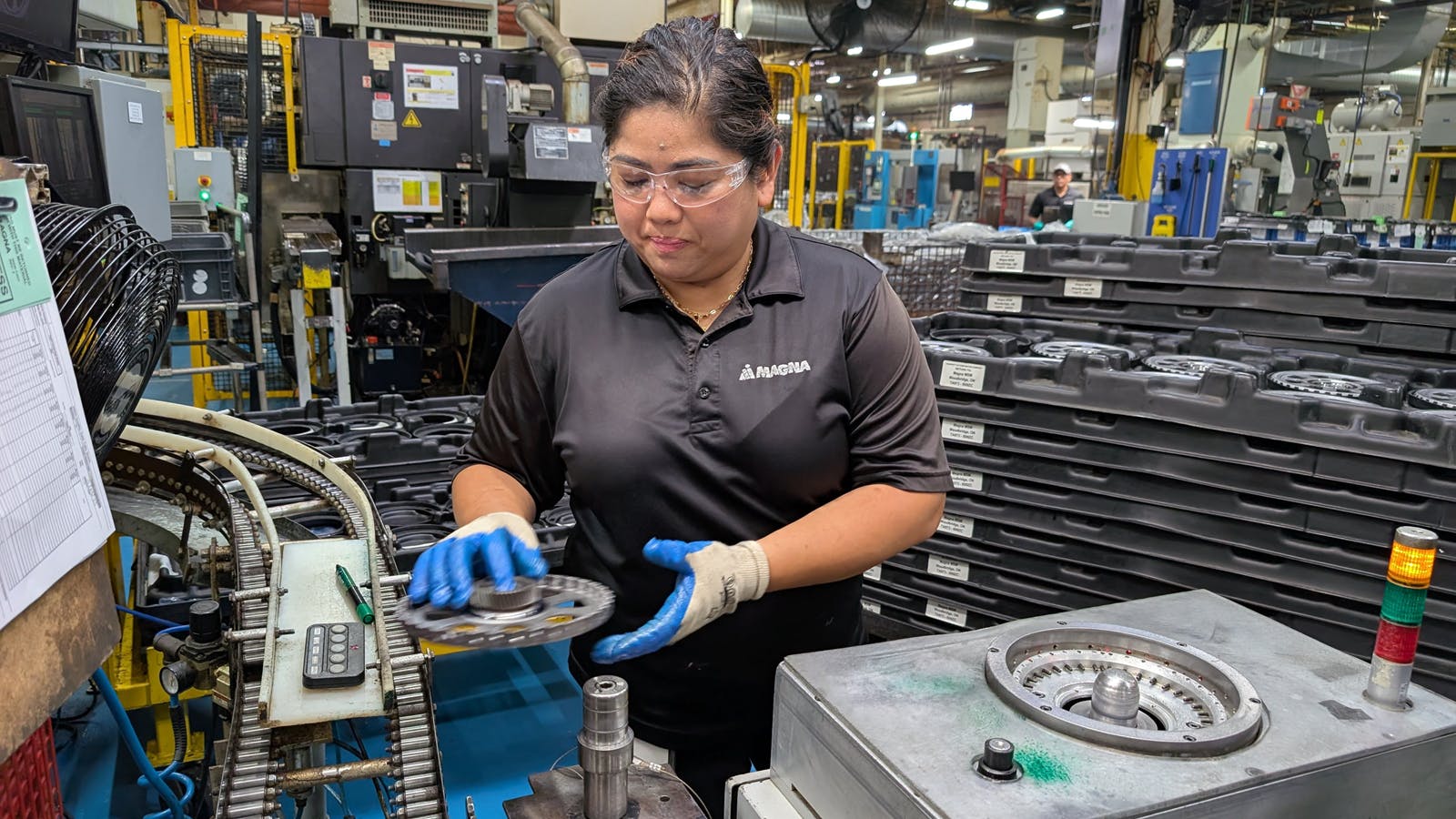 Machine operator Rebecca Asuncion removes a finished part from an outbound conveyor to be placed onto a digital check fixture to then be packed into finished goods.