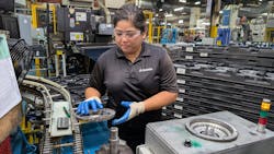 Machine operator Rebecca Asuncion removes a finished part from an outbound conveyor to be placed onto a digital check fixture to then be packed into finished goods. Machine operator Rebecca Asuncion removes a finished part from an outbound conveyor to be placed onto a digital check fixture to then be packed into finished goods.