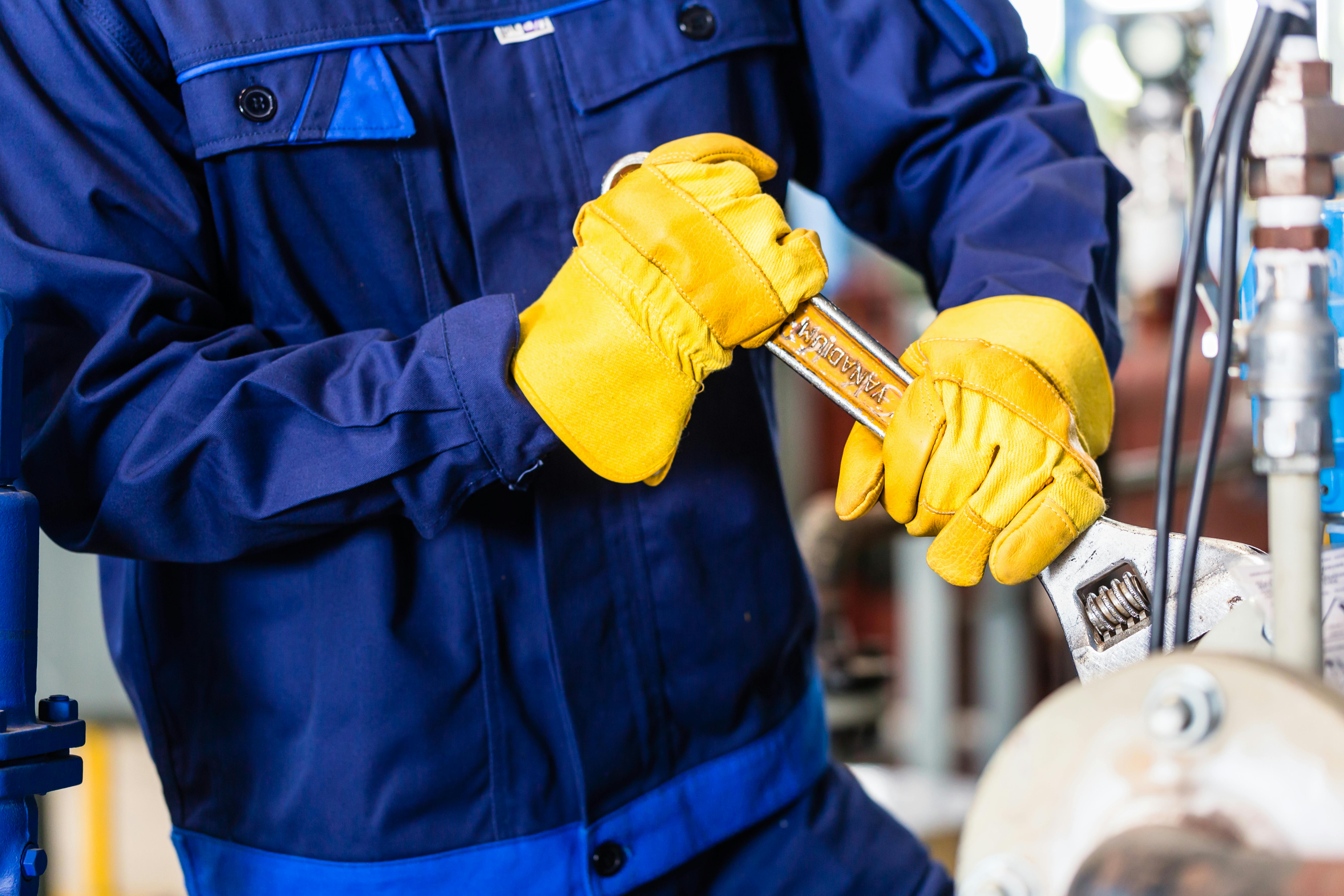 Mechanic repairing machine in industrial plant.