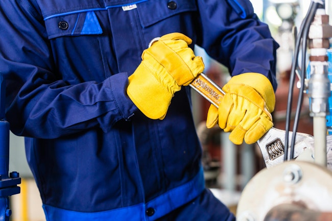 Mechanic repairing machine in industrial plant.