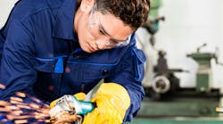 Worker grinding metal in manufacturing plant Worker grinding metal in manufacturing plant