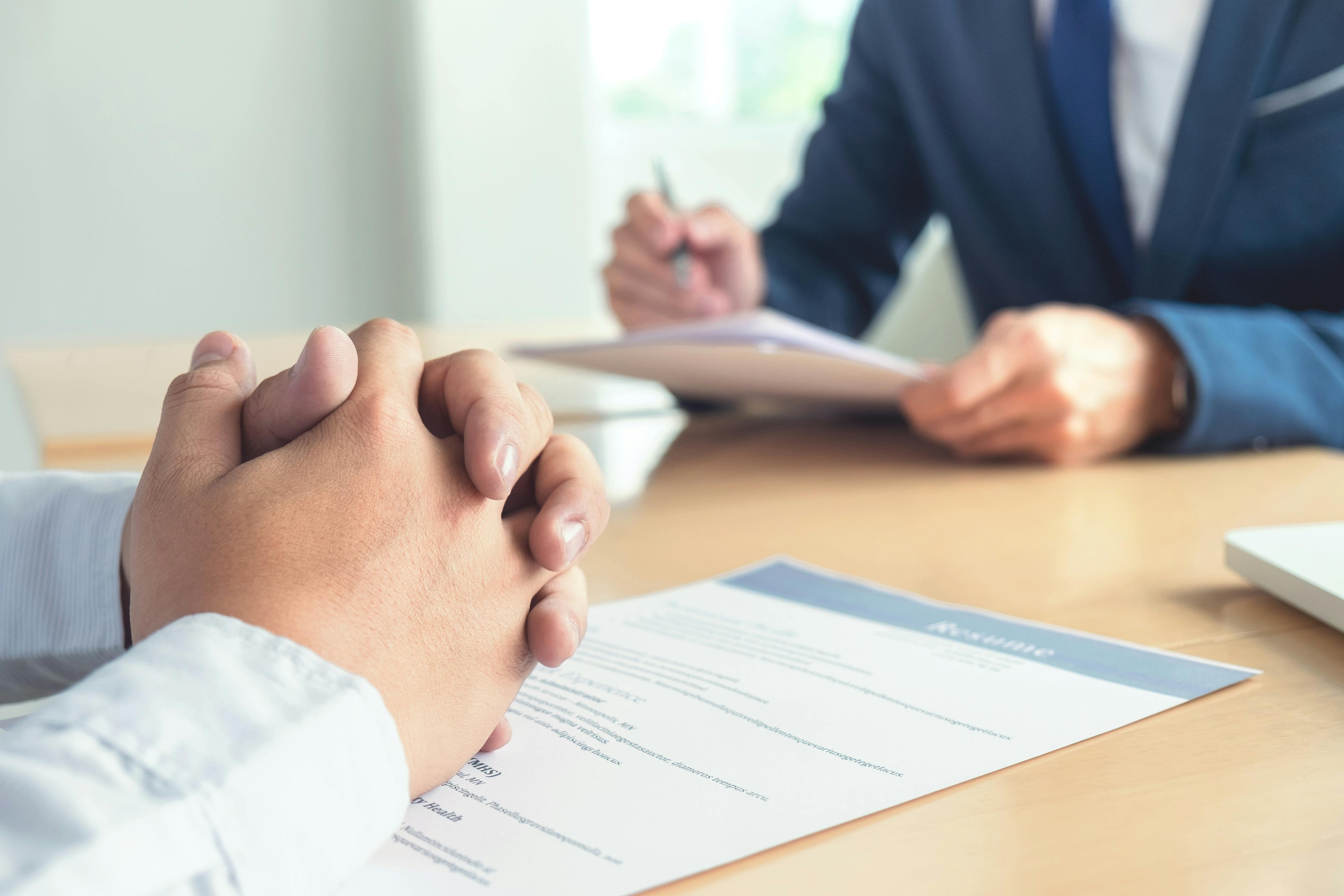 Executive reading a resume during a job interview, and businessman completing application form