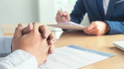 Executive reading a resume during a job interview, and businessman completing application form Executive reading a resume during a job interview, and businessman completing application form