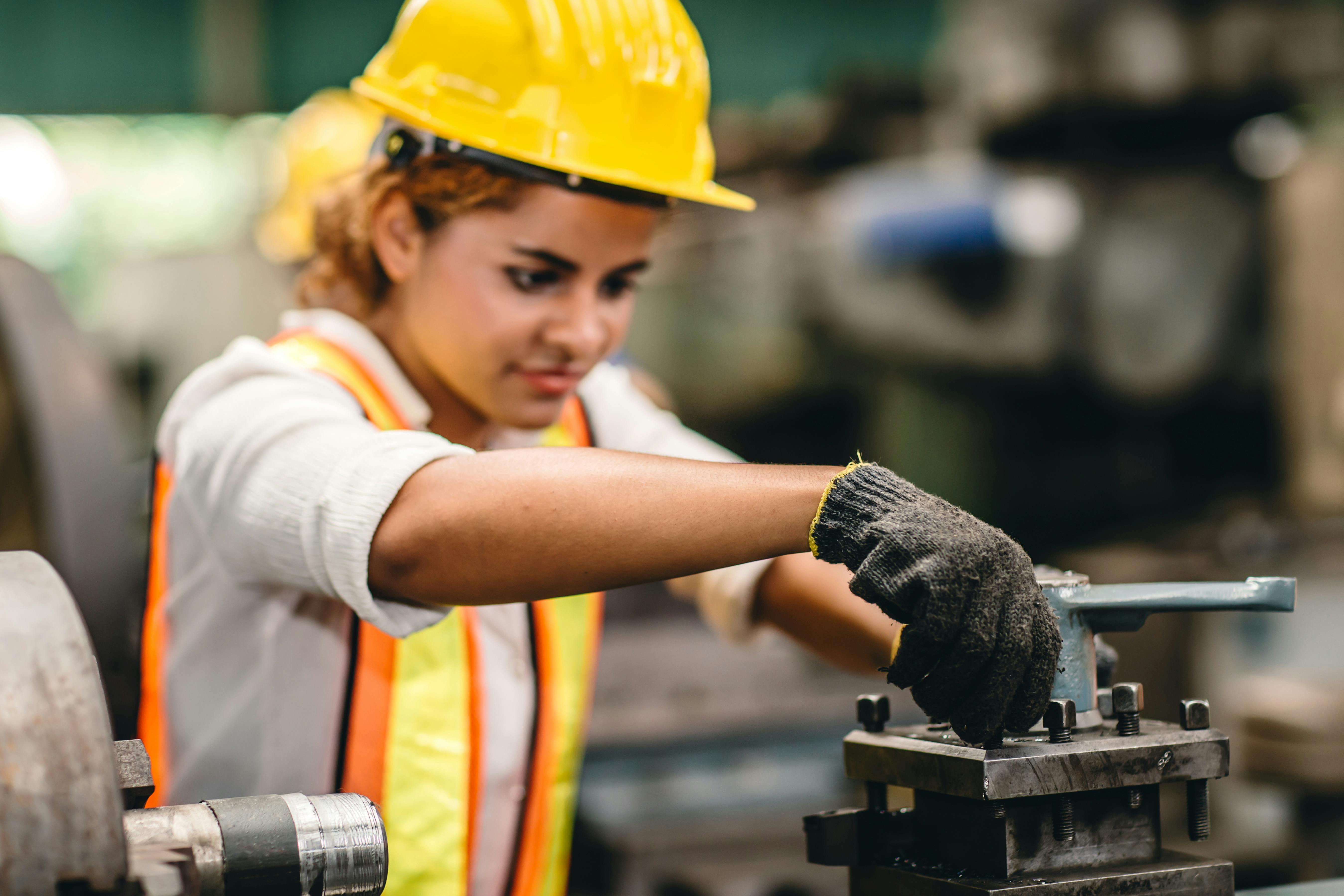 Worker controls metal lathe machine