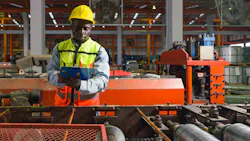 A factory worker standing near a production line conveyor belt