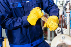 body of person holding a wrench and working on equipment