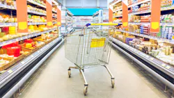 grocery store aisle with empty cart in the middle of it