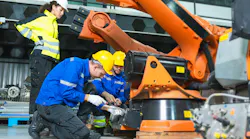 Robotics engineer and technician repairing industrial robot arm in factory