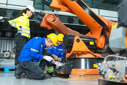 Robotics engineer and technician repairing industrial robot arm in factory
