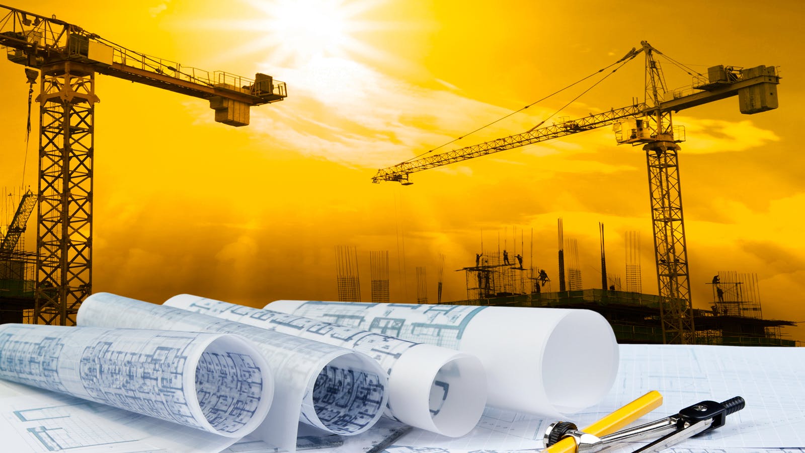 architectural plan on unseen table with construction equipment, such as cranes, in the background.
